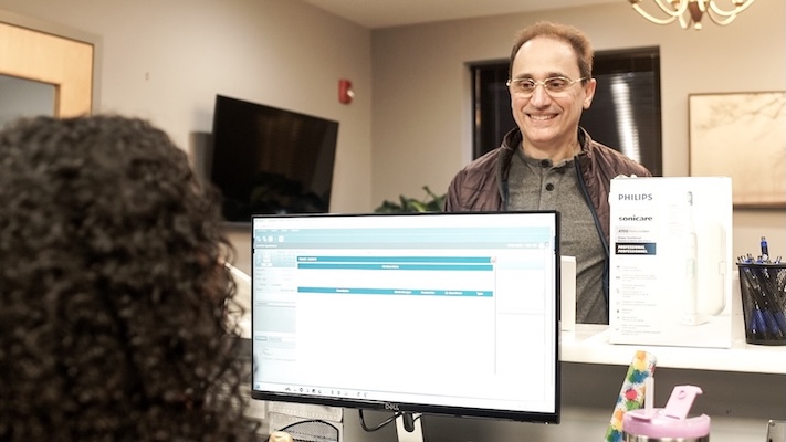 Dental Care of Burlington's Receptionist meeting a smiling patient our Burlington, MA office.