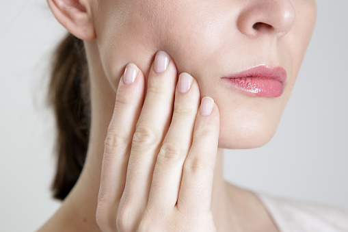 A woman with TMJ pain holding her jaw A woman with TMJ pain holding her jaw