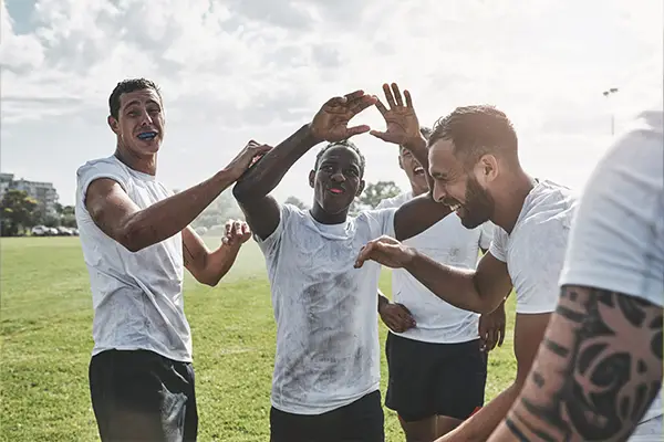 A group of cheerful young rugby players wearing sports guard to protect their teeth celebrate their winning match.